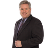 A man in a suit and tie is smiling for the camera