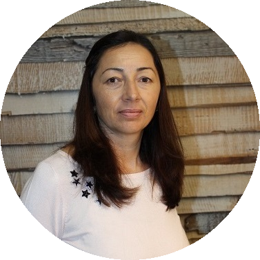 Porträt einer Frau mit dunklen Haaren, die ein weißes Hemd trägt, vor einer strukturierten Holzwand