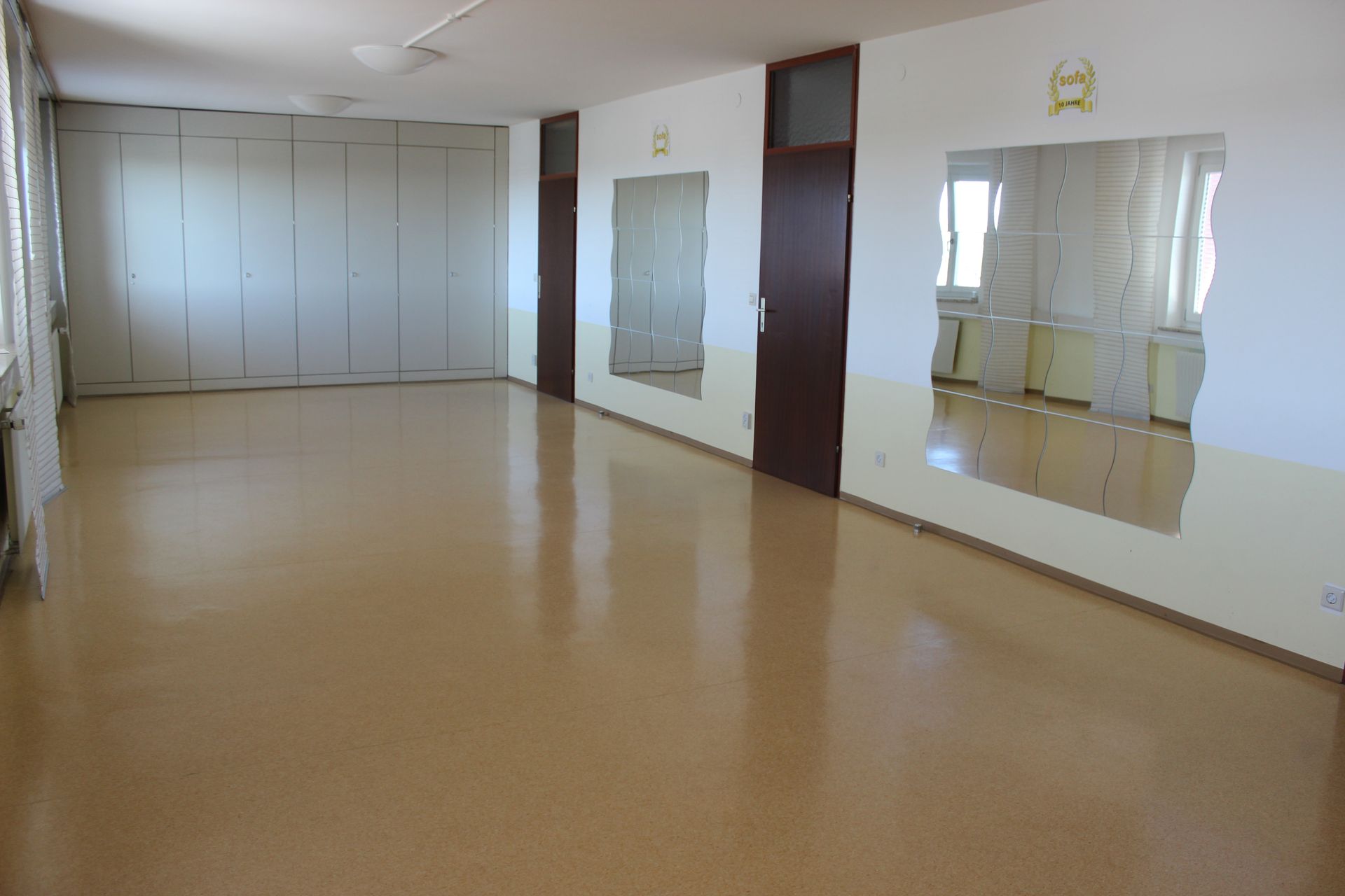 Leeres Tanzstudio mit verspiegelten Wänden, Ballettstangen und hellem Holzboden