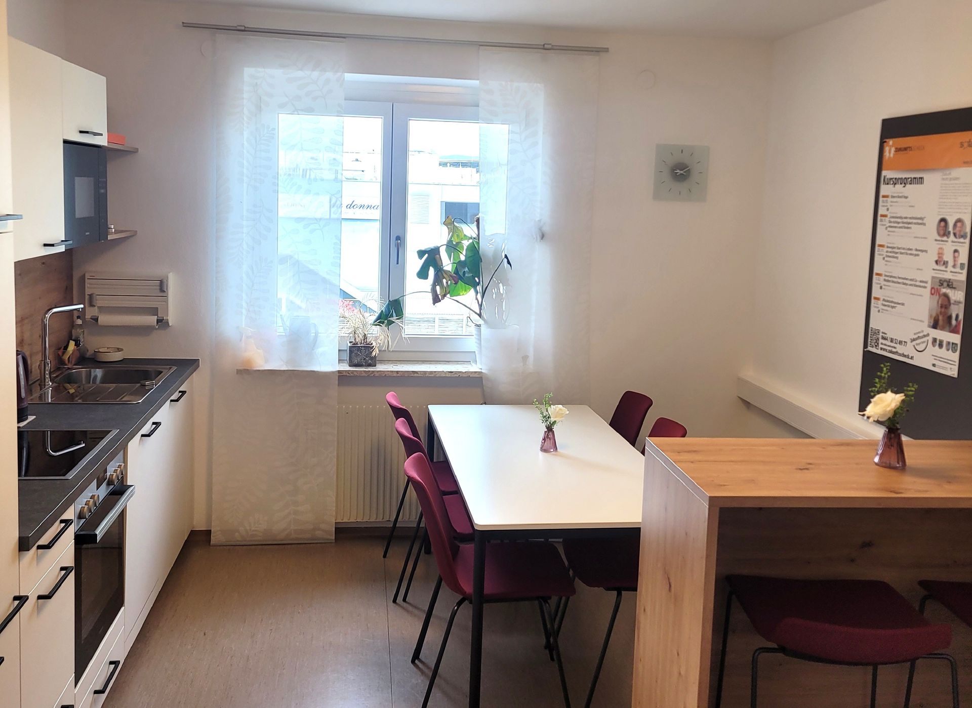 Helle Küche mit Esstisch, Stühlen, Fenster und Herd an der linken Wand