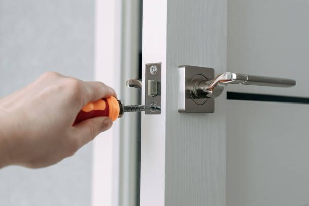 A person is fixing a door handle with a screwdriver.