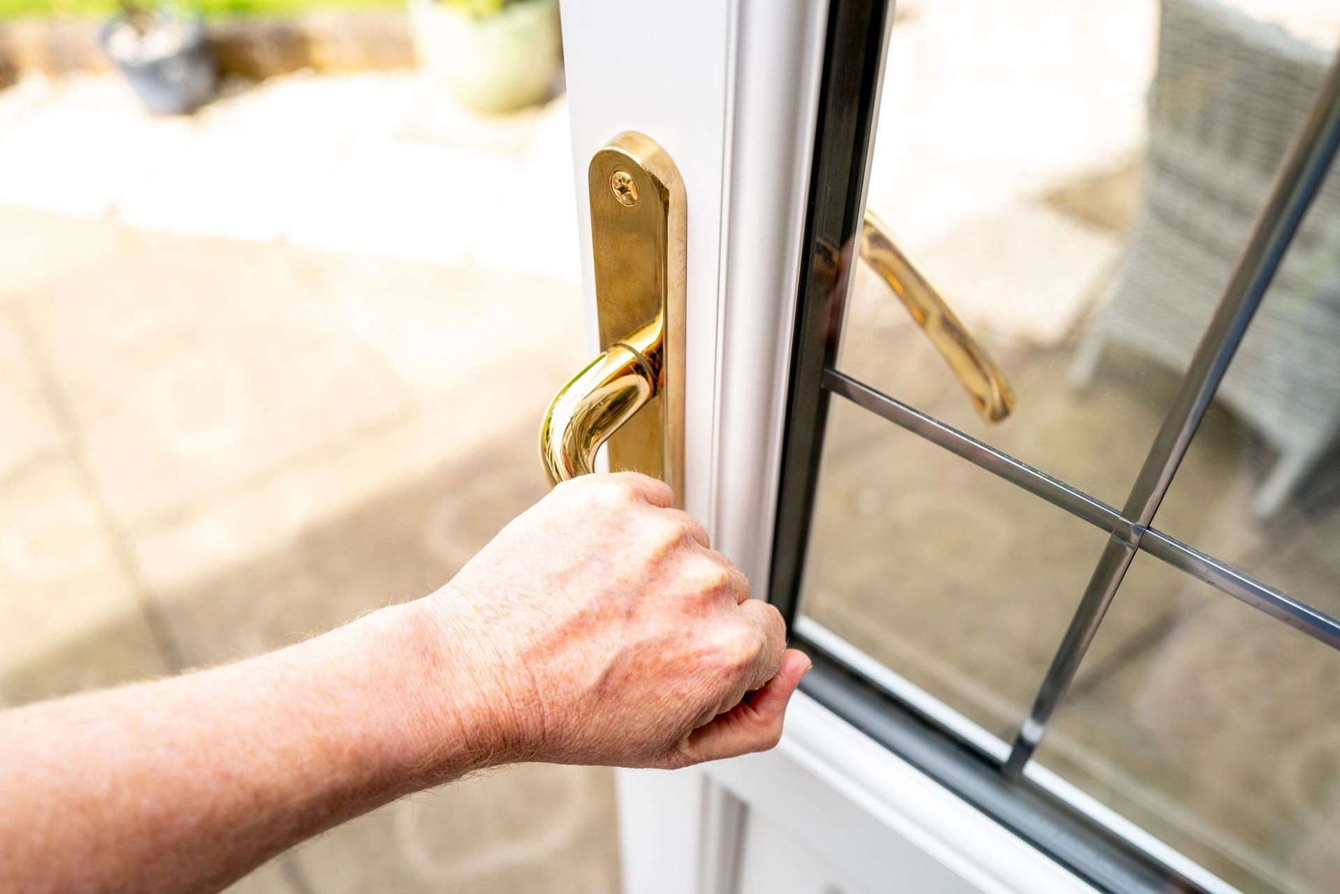 A person is opening a sliding glass door with their hand.