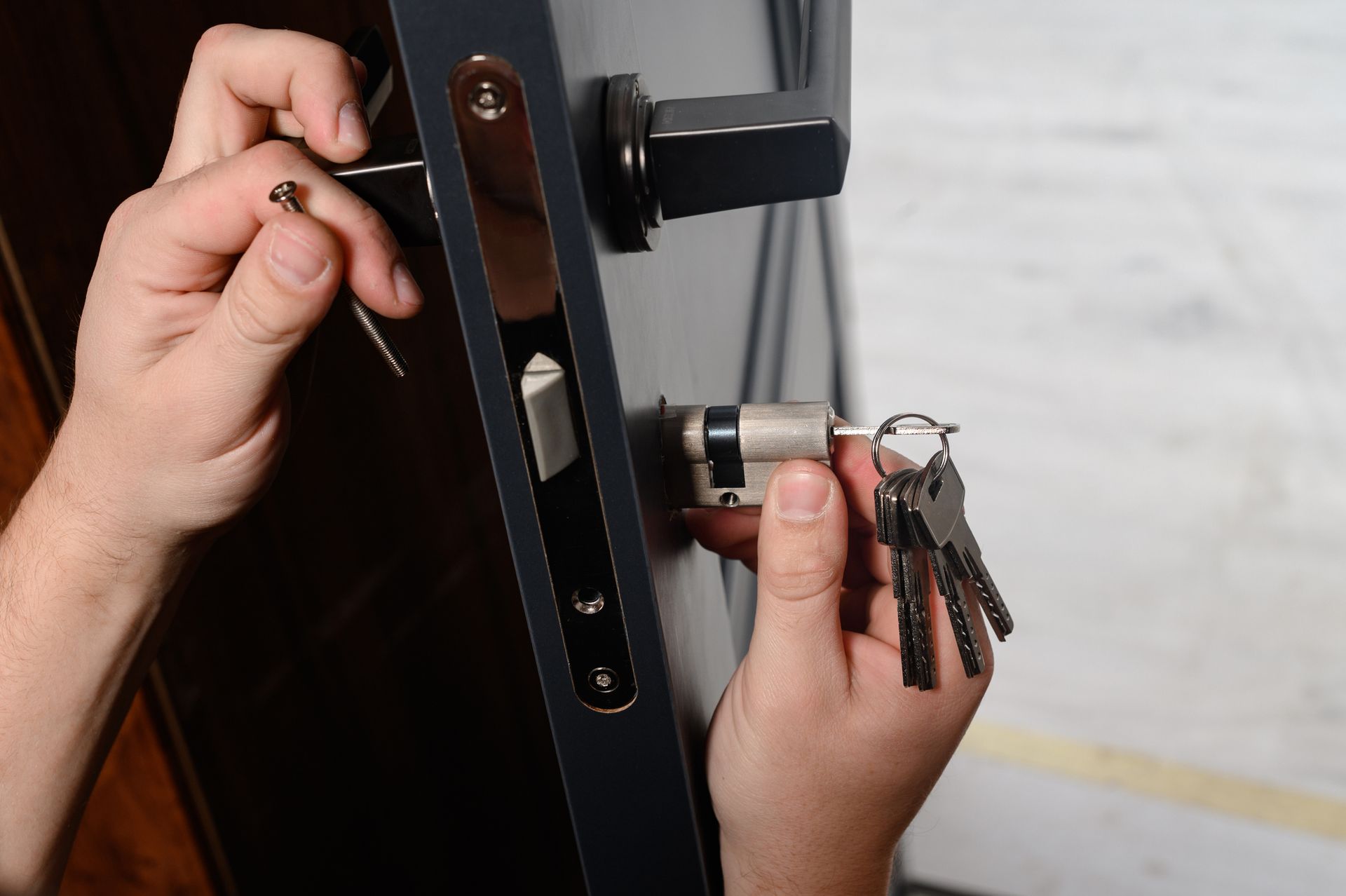 A person is fixing a door lock with a wrench and keys.