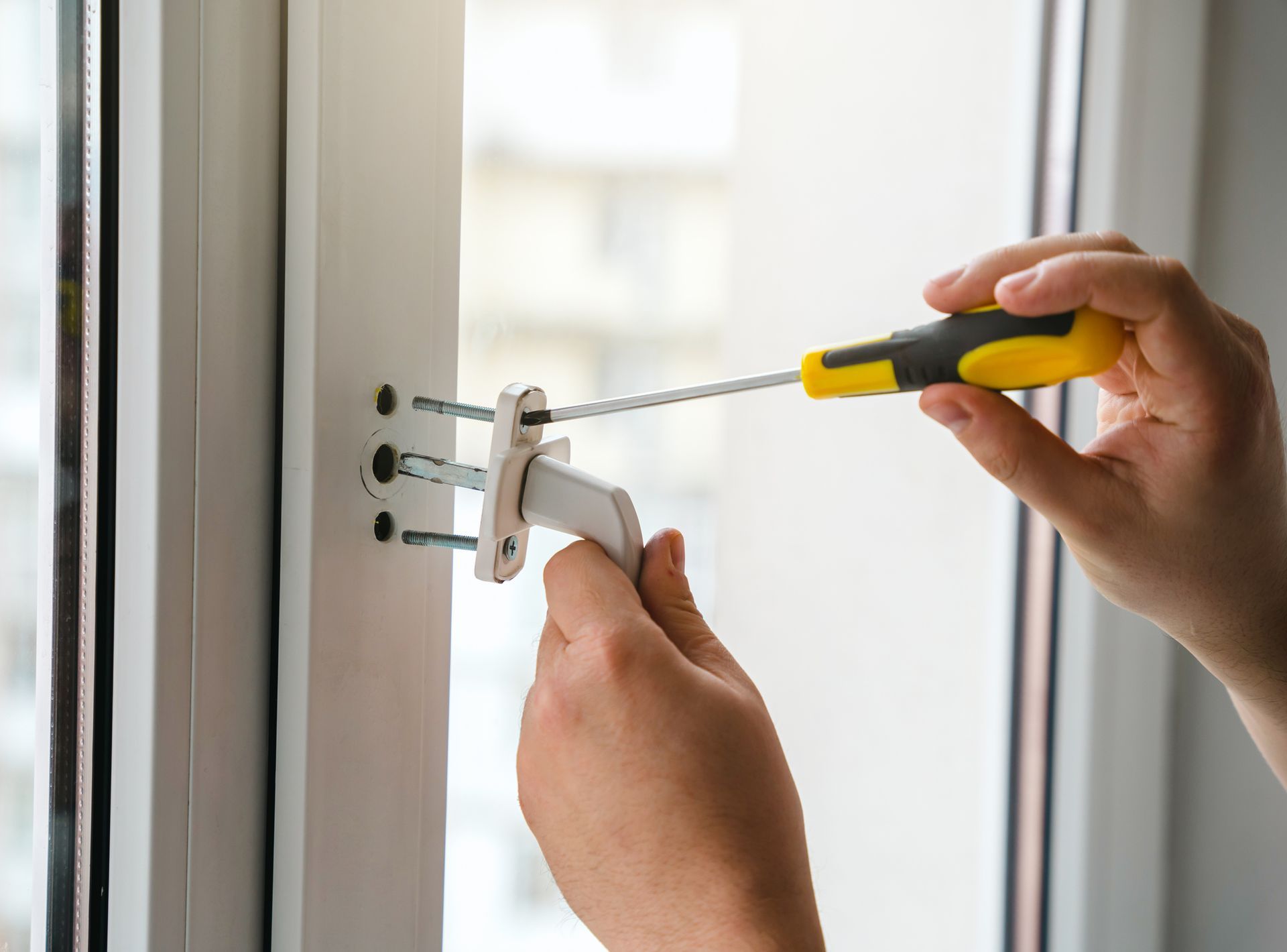 A person is fixing a door handle with a screwdriver. A person is fixing a door handle with a screwdriver.