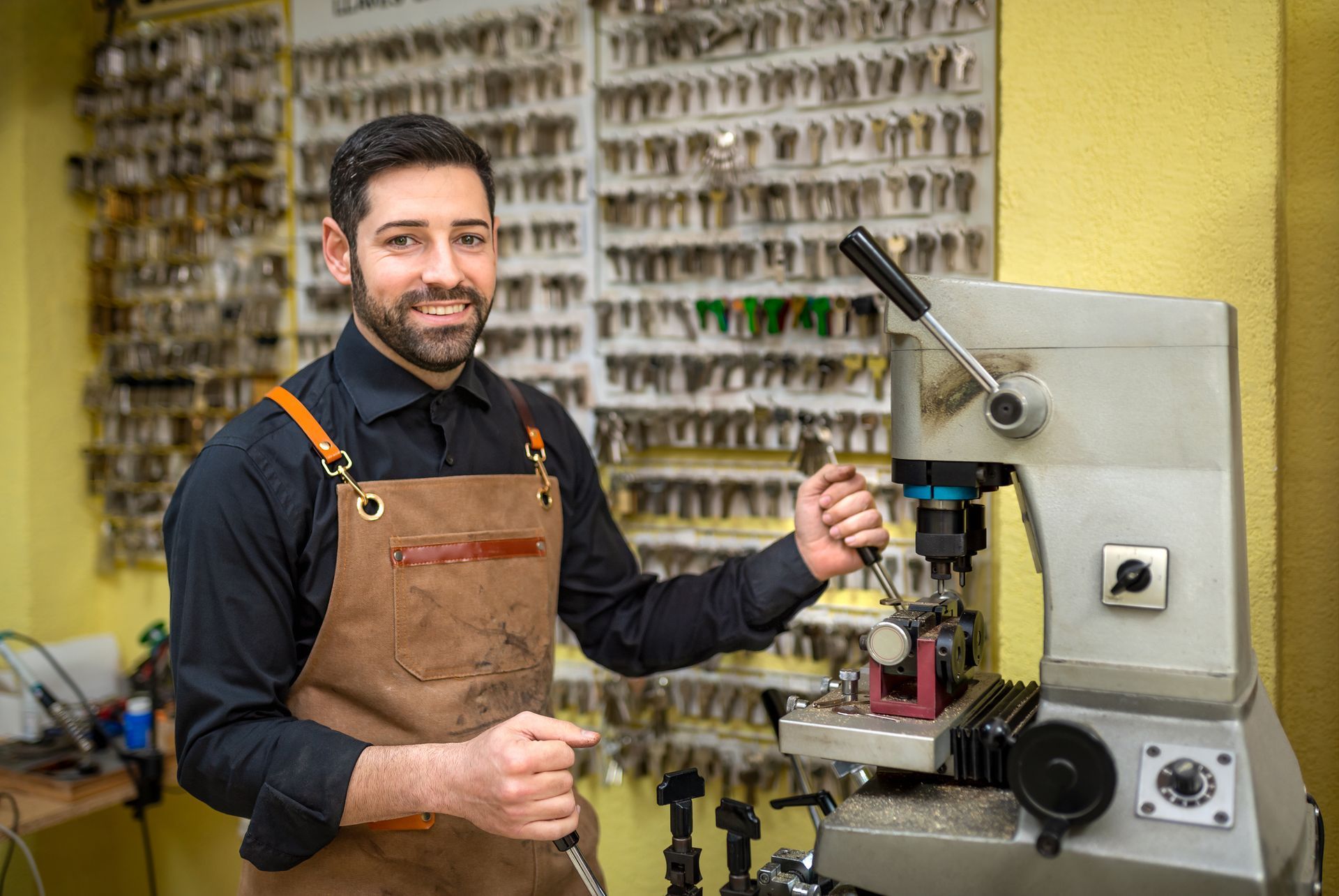 A man is standing in front of a machine in a locksmith shop. A man is standing in front of a machine in a locksmith shop.