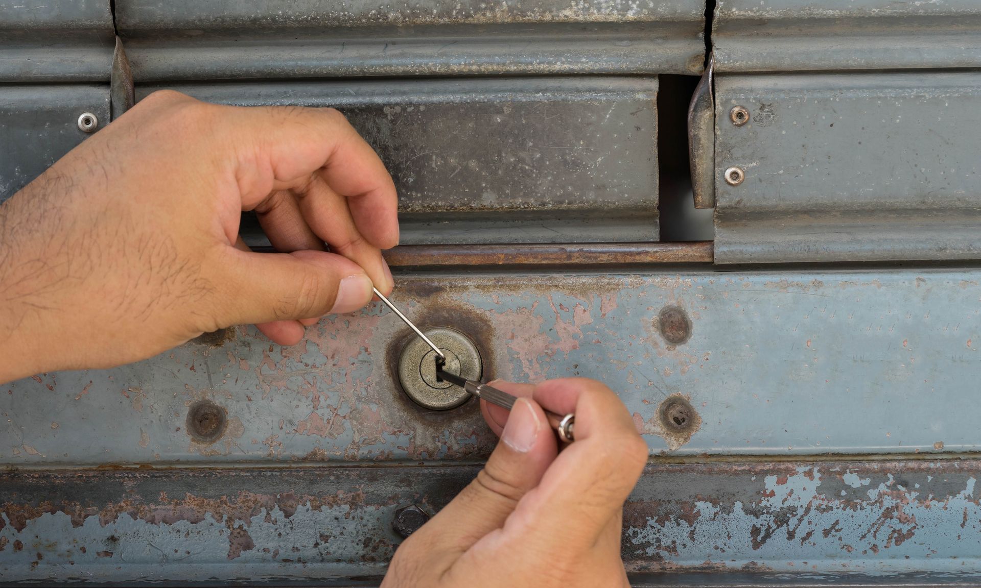 A person is using tools to open a door lock.