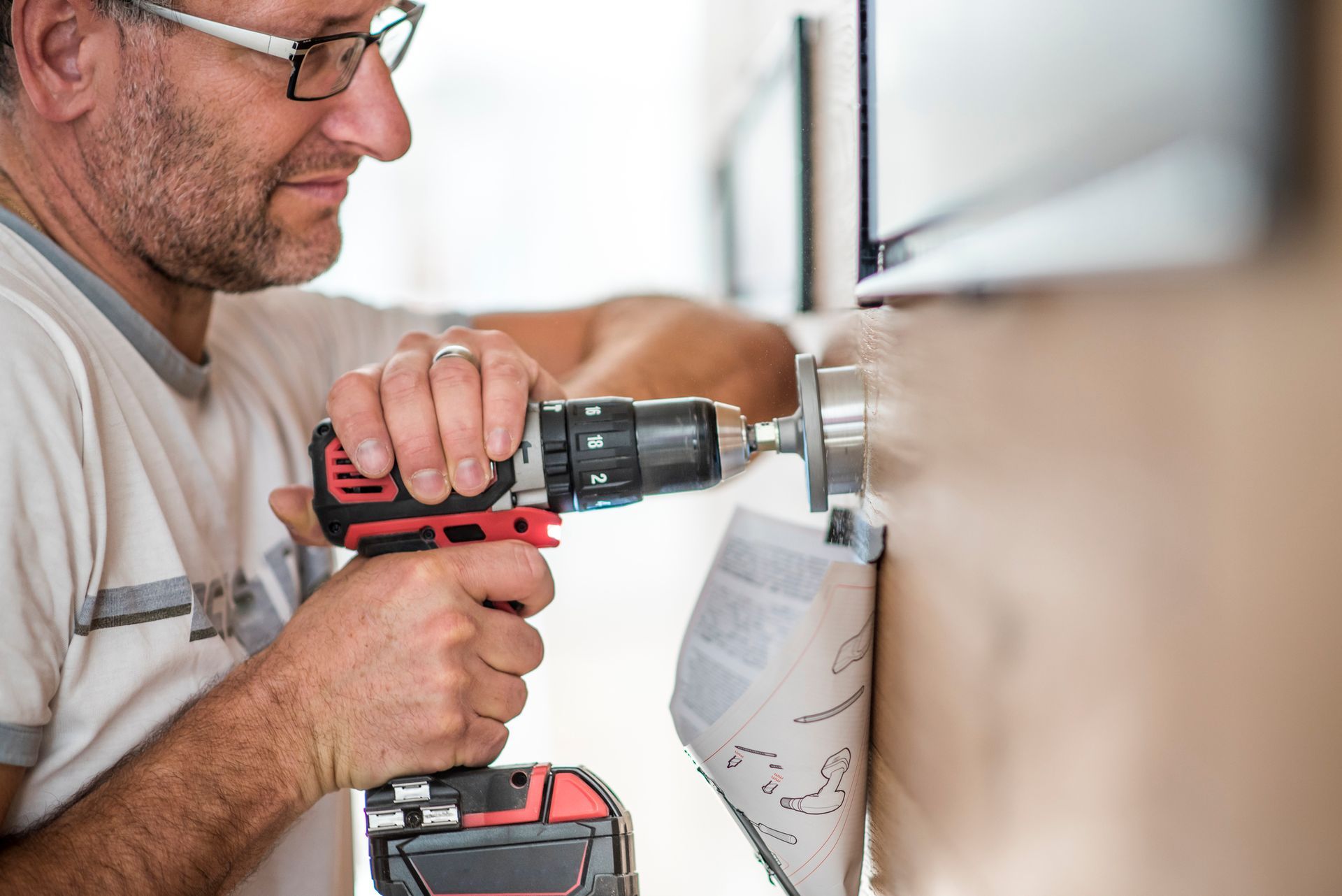 A man is using a drill on a wall.