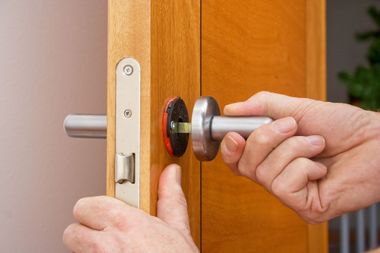 A person is installing a door handle on a wooden door.