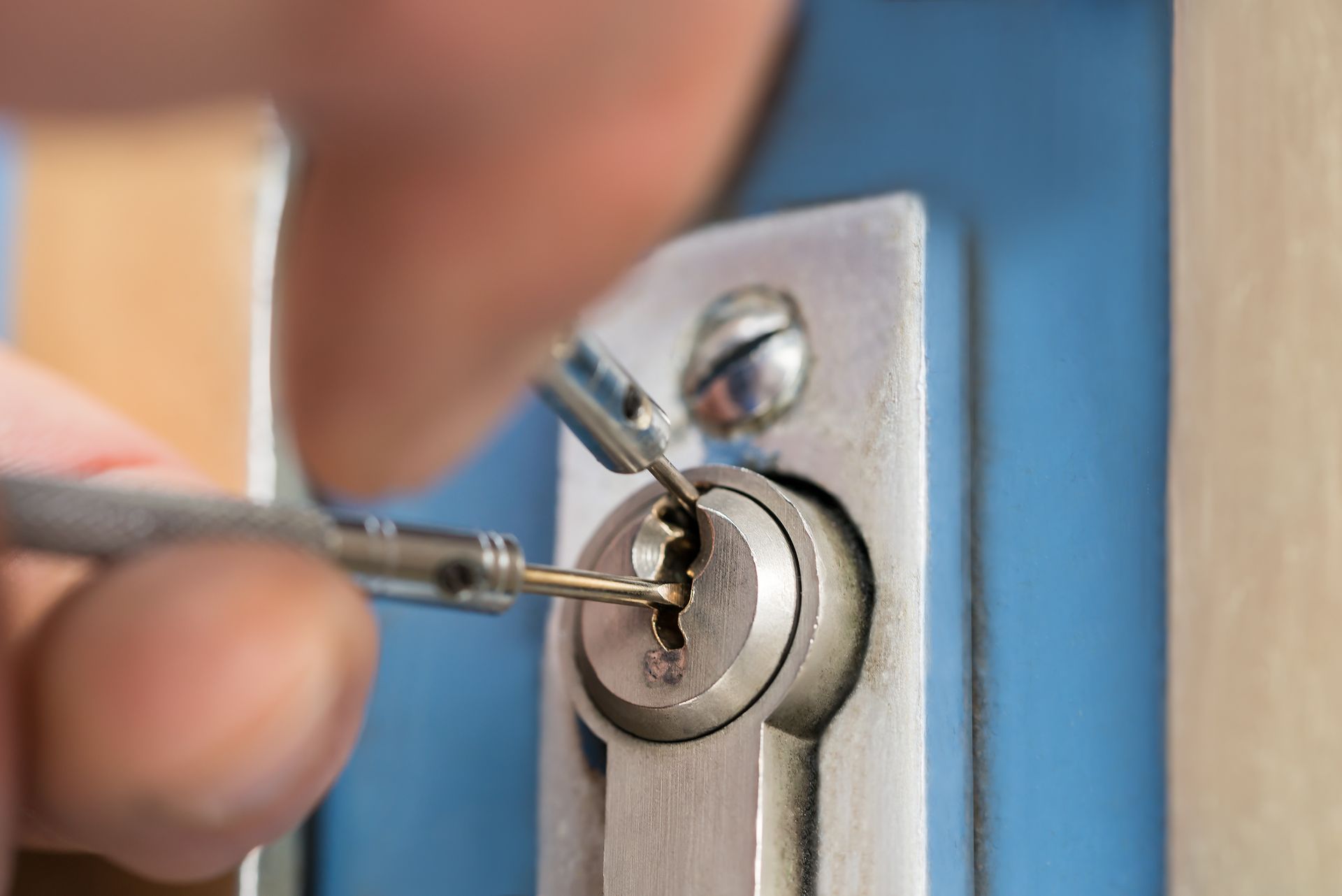 A person is using a screwdriver to open a door lock.