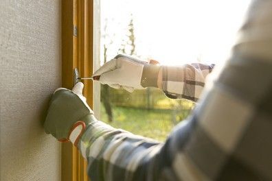 A man is fixing a door with a screwdriver.