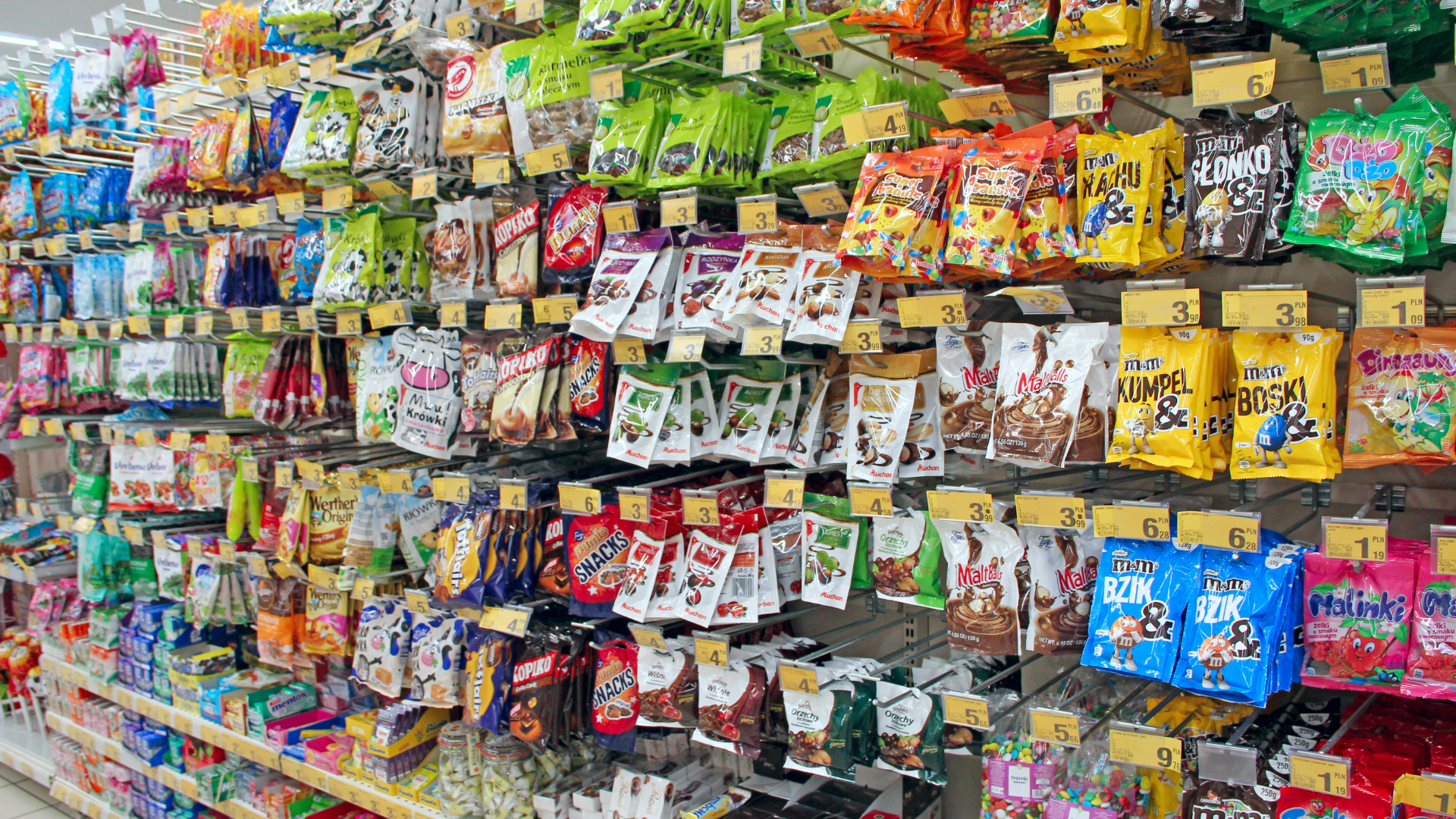 A grocery store aisle filled with lots of bags of candy.