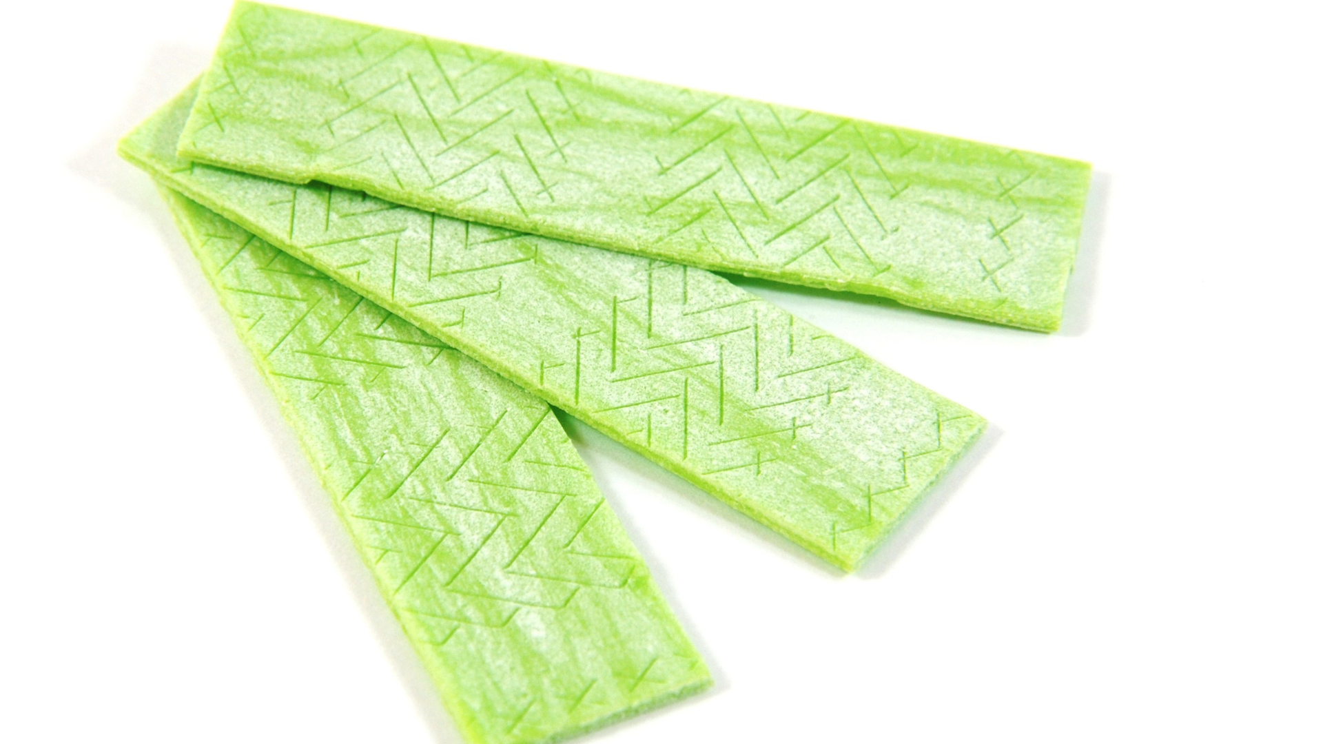 Three pieces of green gum on a white background.