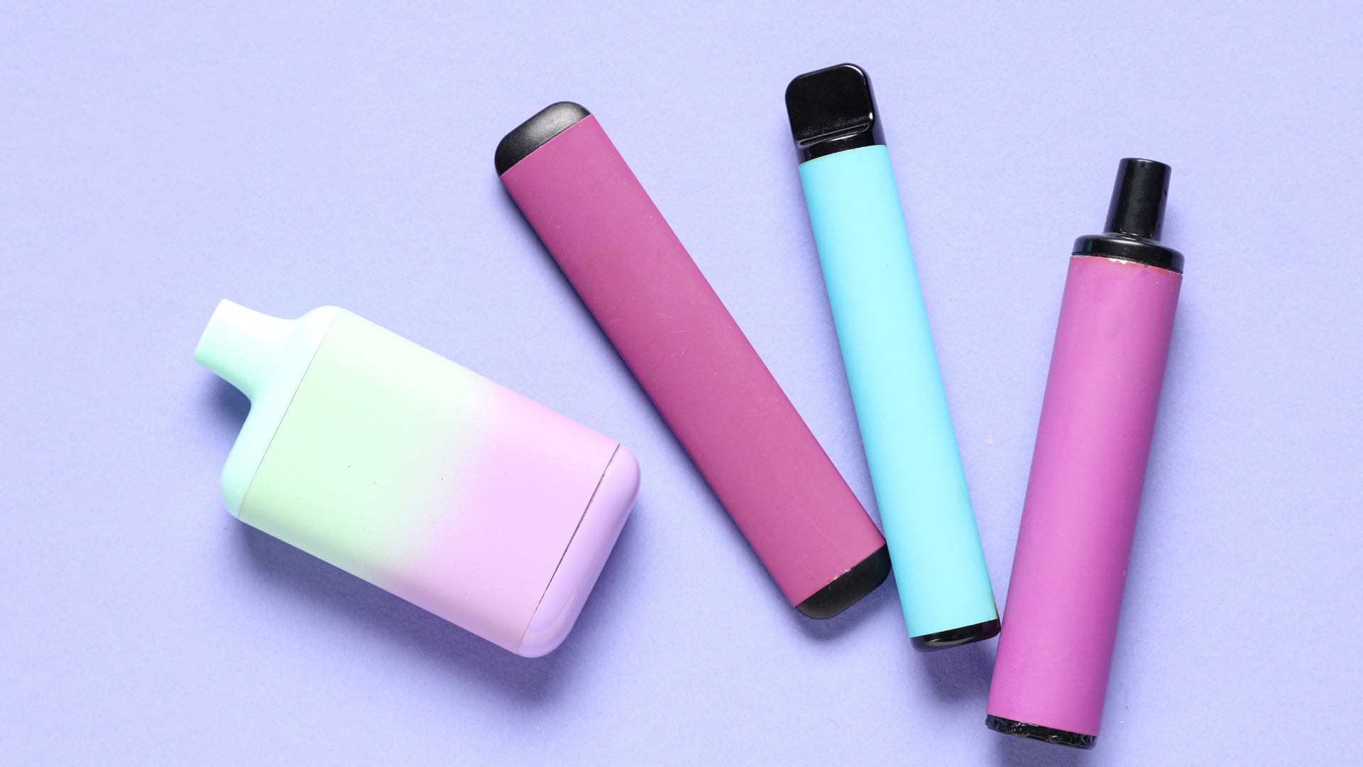 A group of electronic cigarettes are sitting on top of each other on a purple surface.