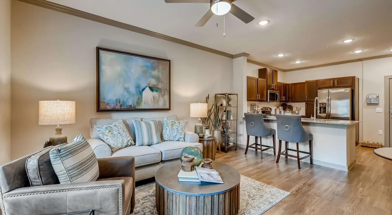 Open-concept living room with beige sofa, decorative pillows, coffee table, and a kitchen island.