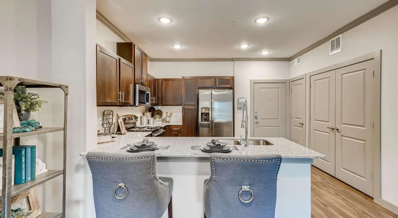 Bright kitchen with granite island, dark wood cabinets, stainless steel appliances, and bar seating.