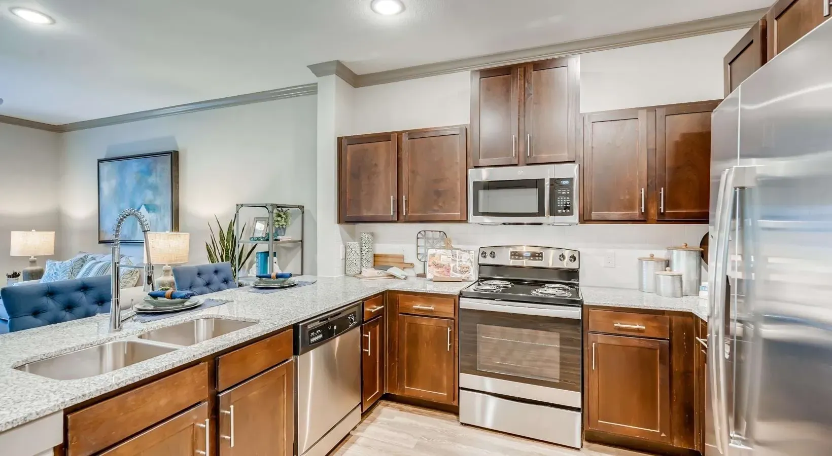 Kitchen in a modern apartment with dark wood cabinets, stainless appliances, and granite countertops.