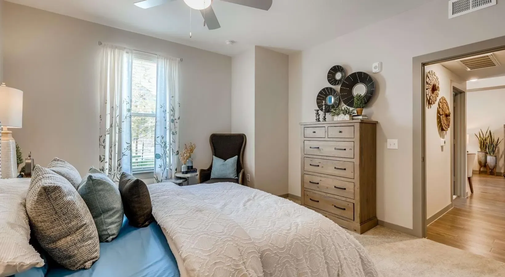 Bedroom in an apartment with a bed, dresser, chair, and window.