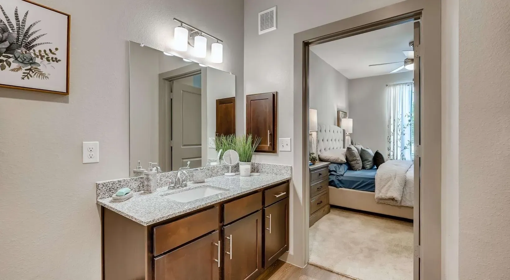 Vanity area with granite counter, sink, and large mirror; doorway to the bedroom.