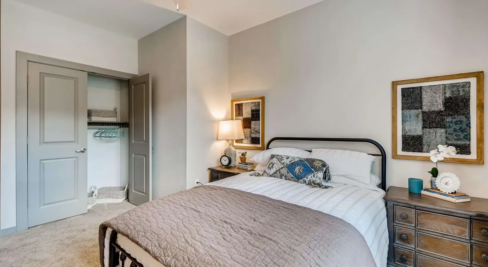 Bedroom with a metal bed frame, two nightstands, soft lighting, and an open closet.