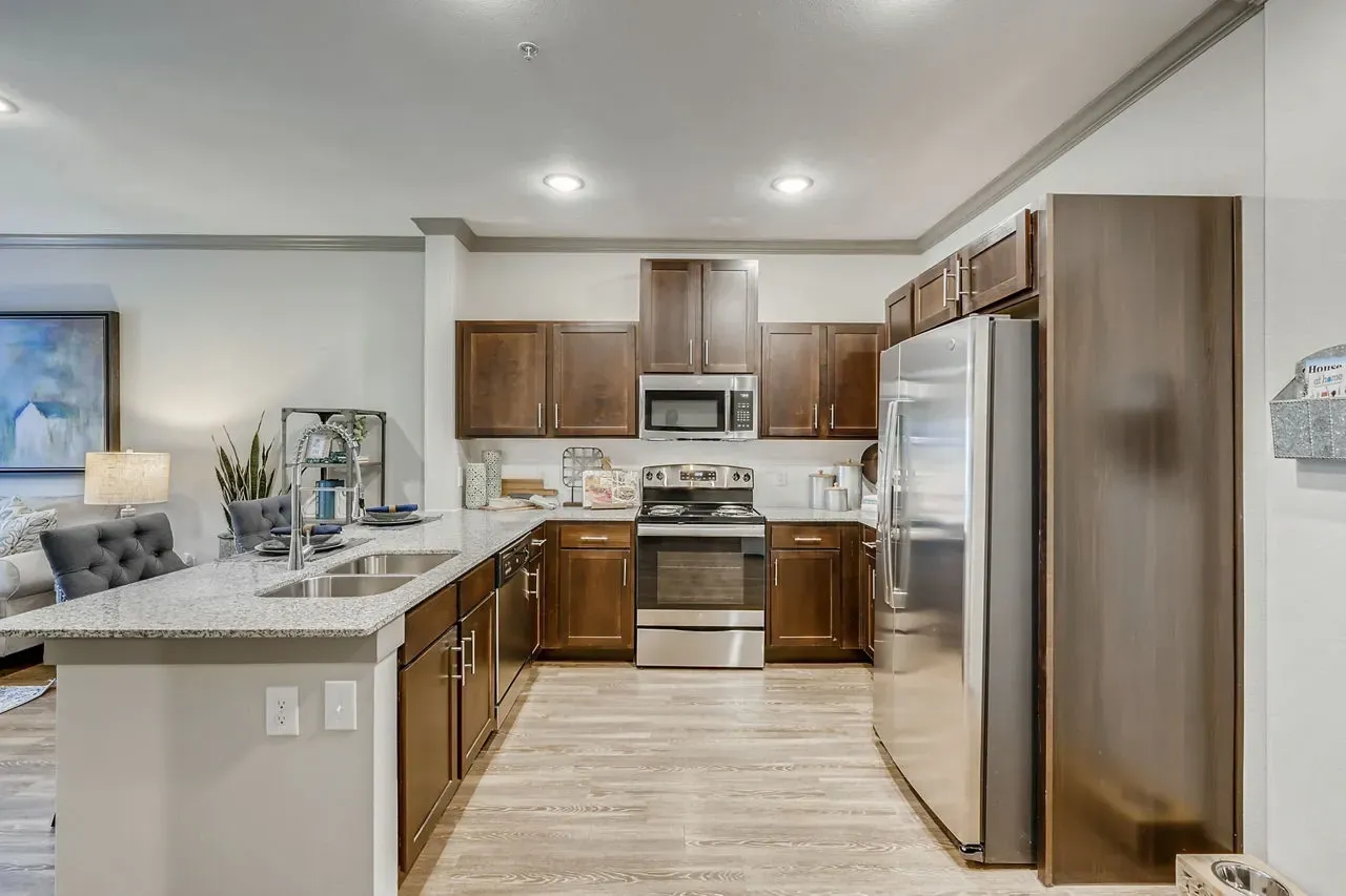 Modern kitchen with dark wood cabinets, stainless steel appliances, and a granite island.