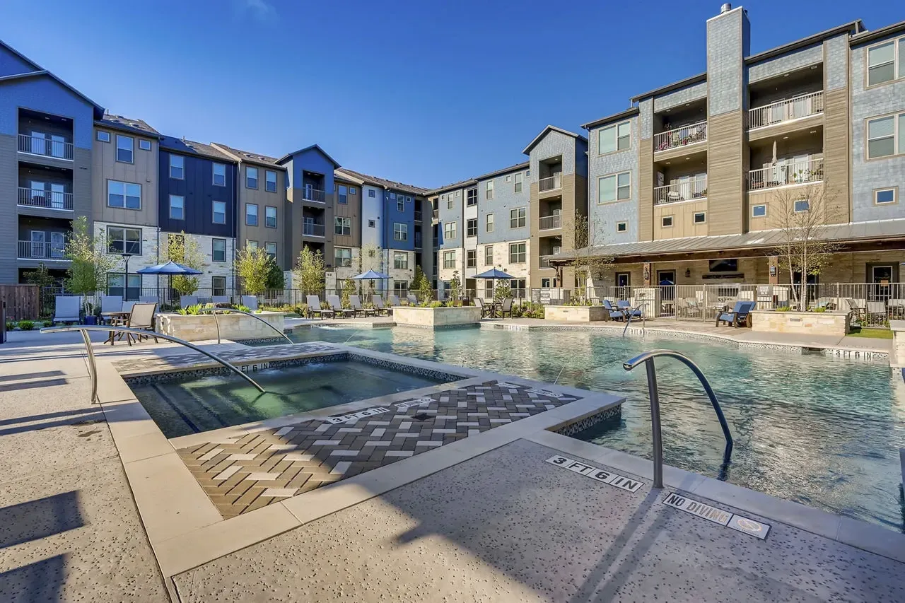 Outdoor pool at a multifamily community with lounge chairs and surrounding buildings.