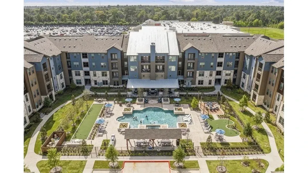 Aerial view of a multi-building apartment complex with a central pool and lounge areas.