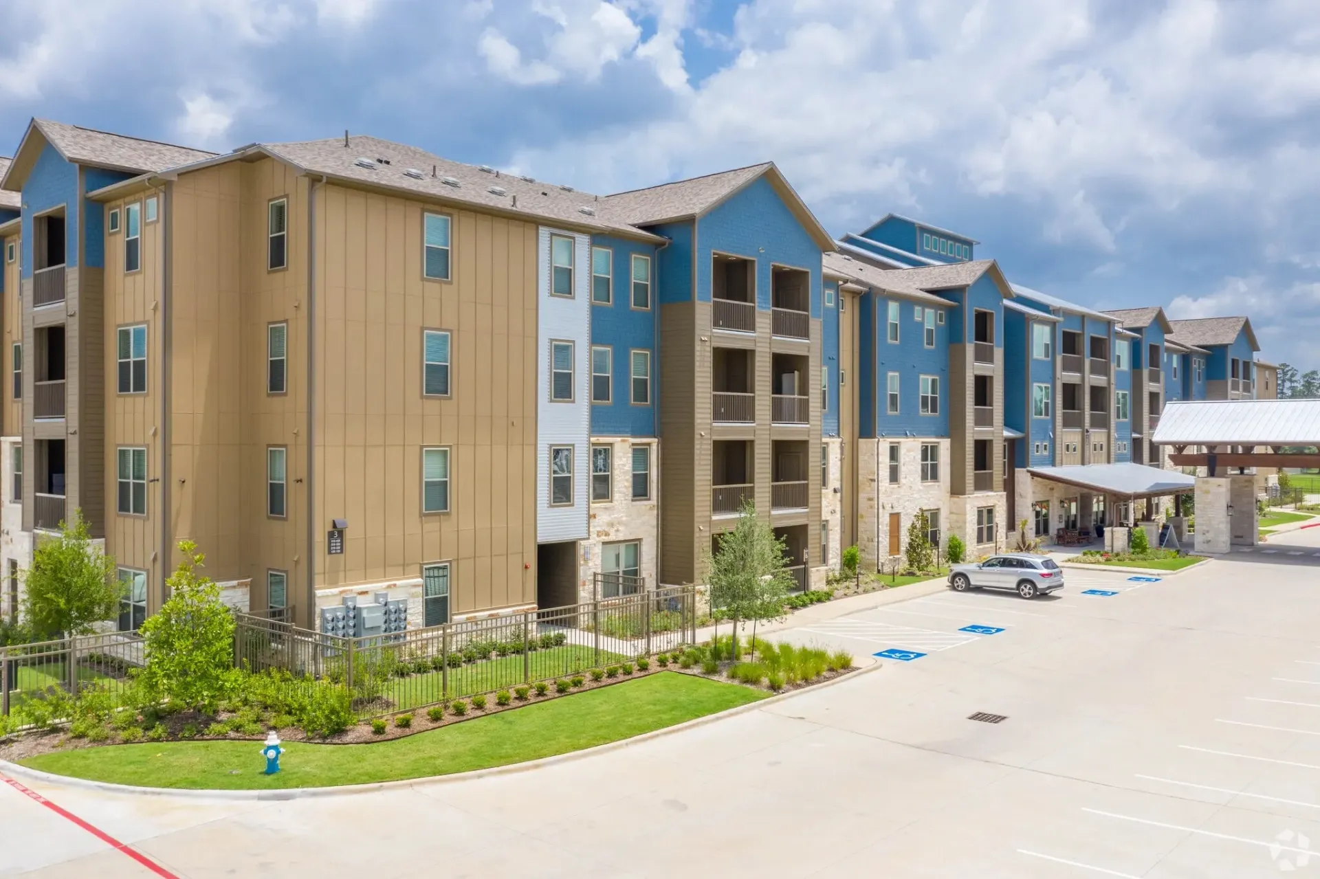 Exterior view of a modern multi-building apartment community with blue and tan siding.