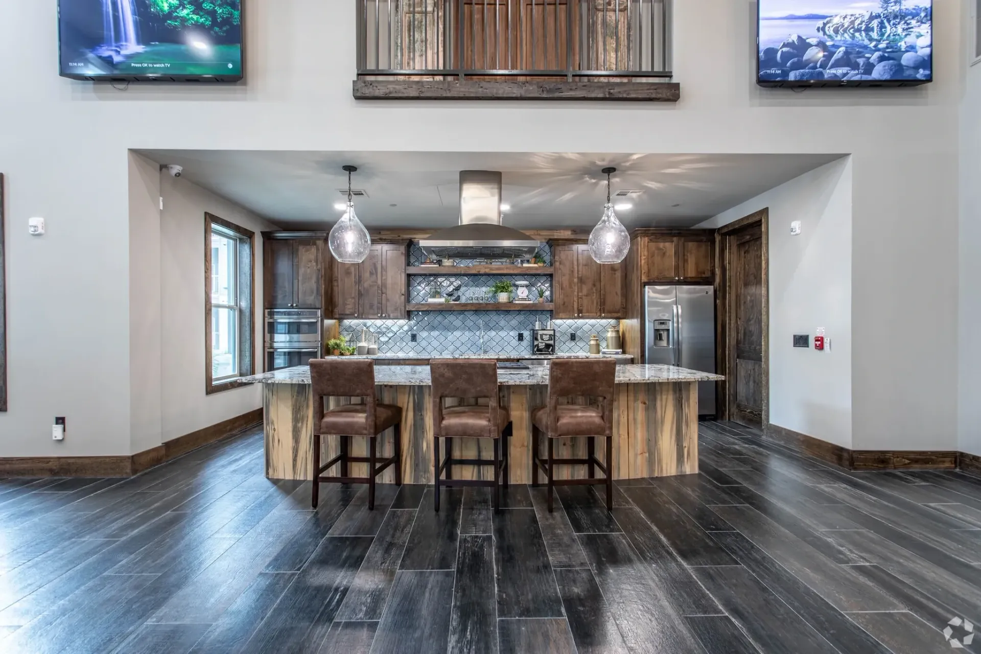 Community kitchen area with granite island, pendant lights, and stainless appliances.