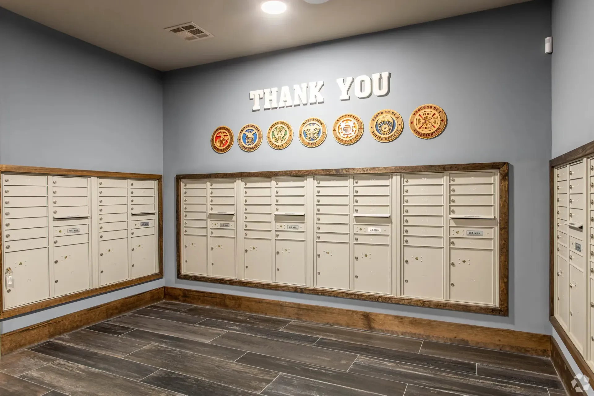 Lobby mailroom with rows of white mailboxes along blue walls and a 'THANK YOU' sign.