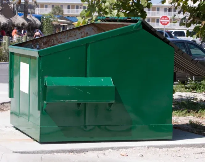 A green dumpster with a no parking sign in the background