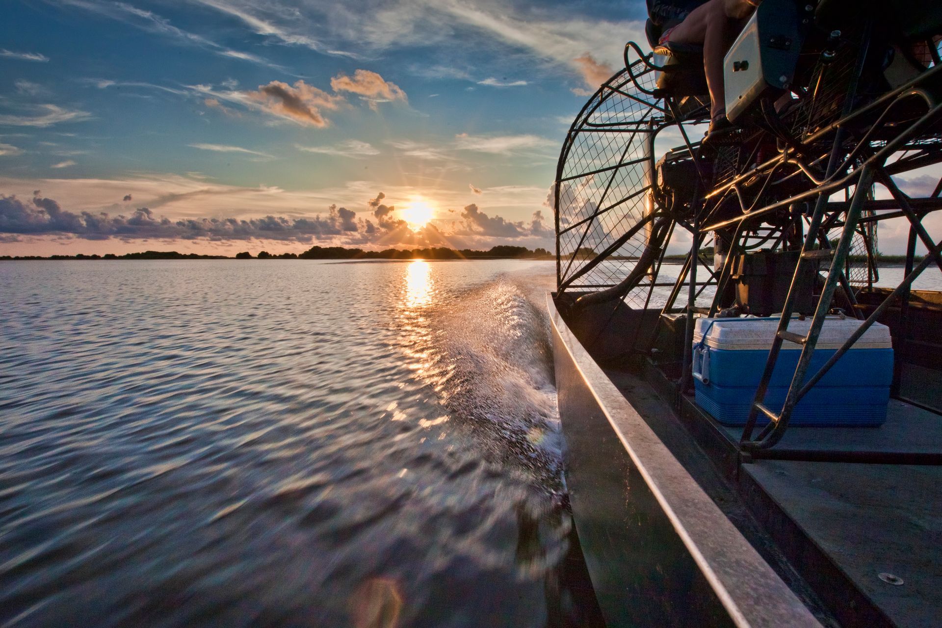 A person is riding a boat on a lake at sunset.