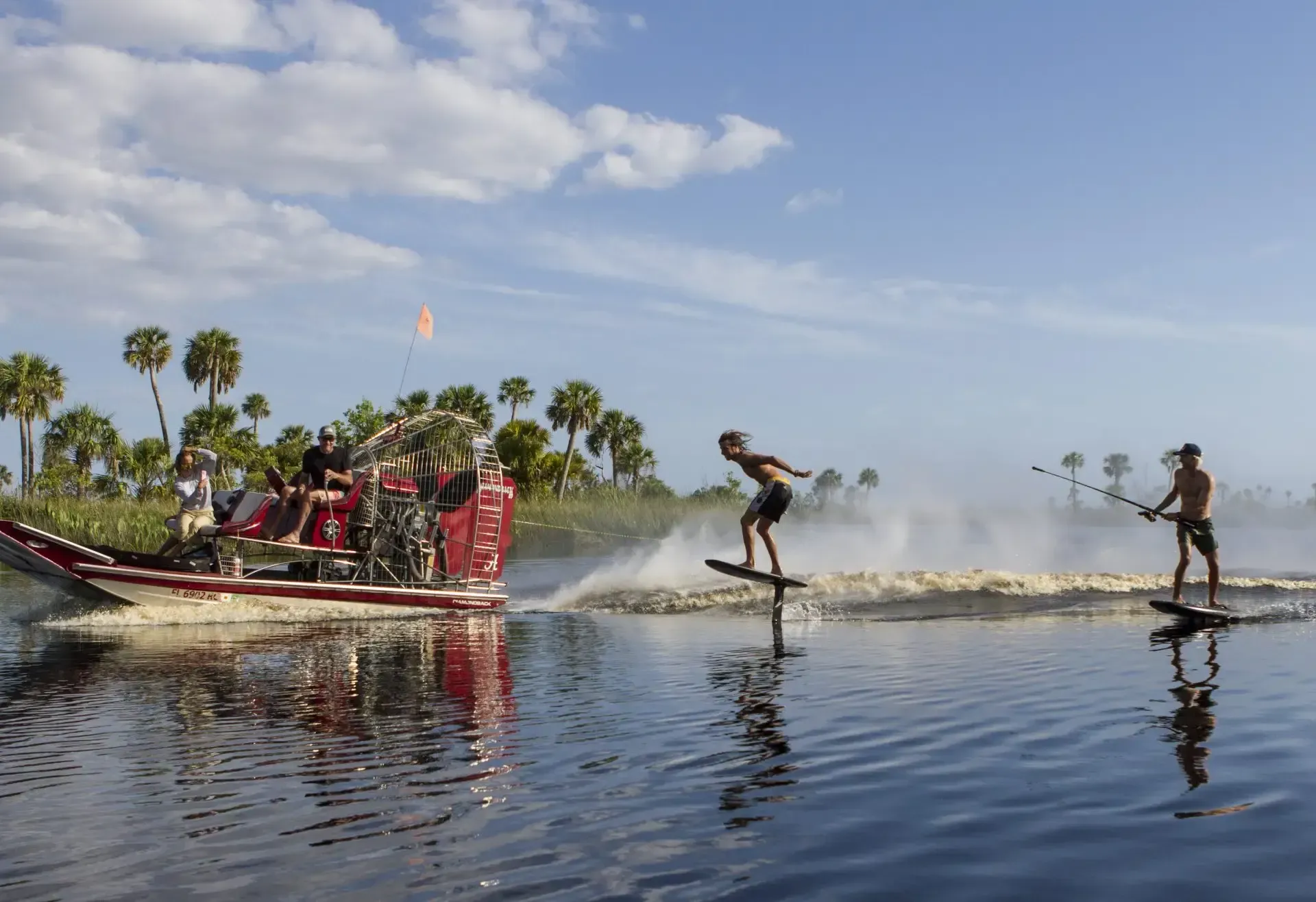 A group of people are water skiing on a lake next to a boat.