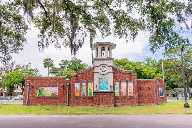 A brick building with a clock tower and paintings on the side of it.