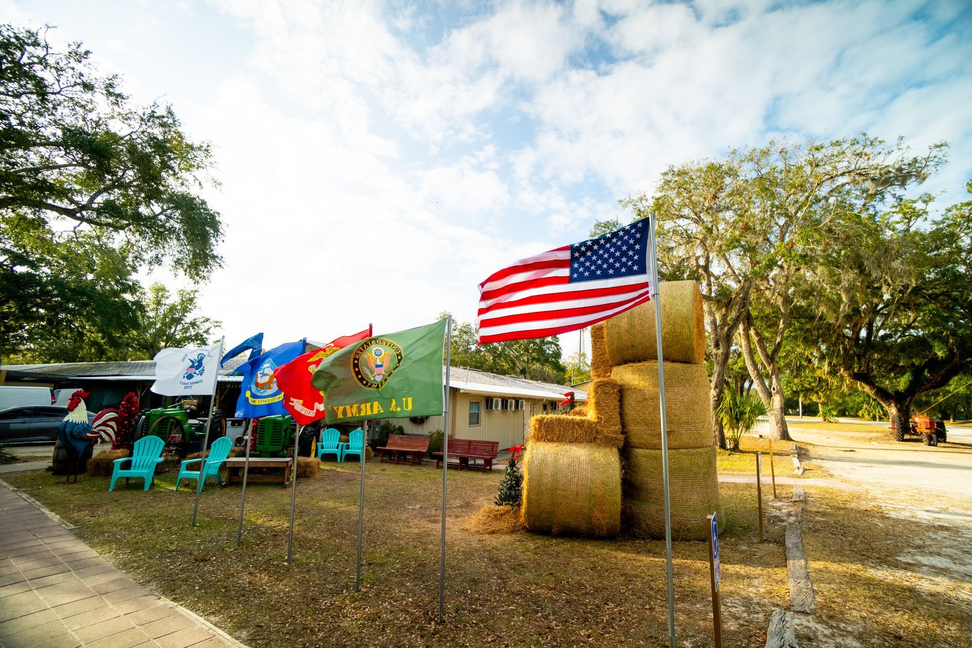 A bunch of flags are flying in front of a stack of hay bales