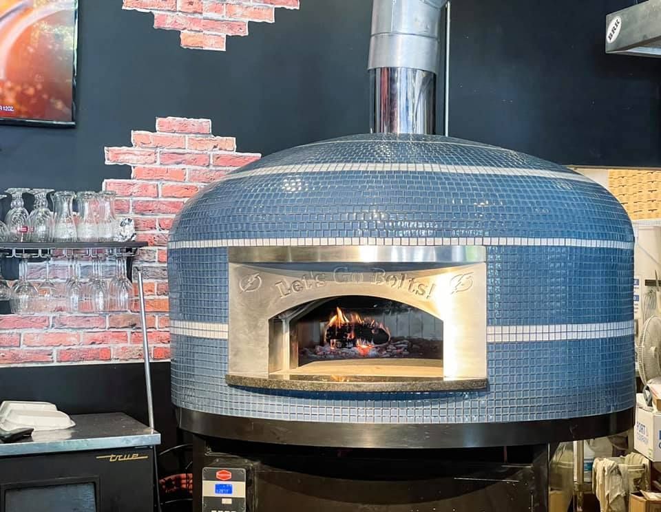 Blue tiled pizza oven with a lit fire.