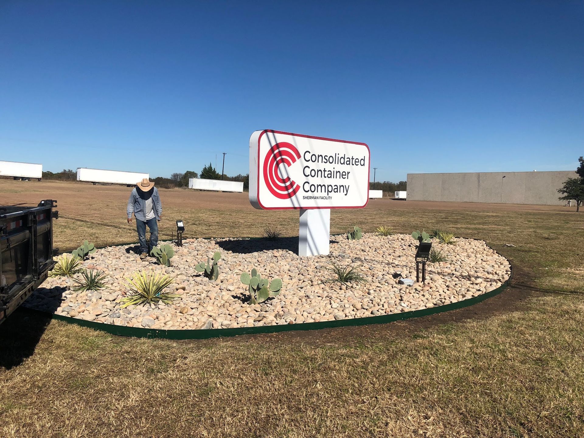 Sign for Cargo Loaded Container Company, in a landscaped area, with a person nearby.