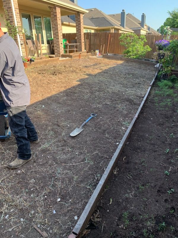 Man standing in backyard with a prepared area for landscaping; a shovel lays on the dirt.