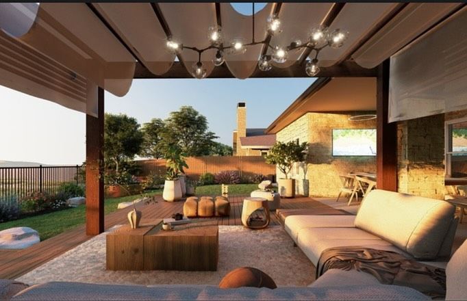 Outdoor patio with seating, wooden table, and string lights. Lush garden and home exterior in the background.