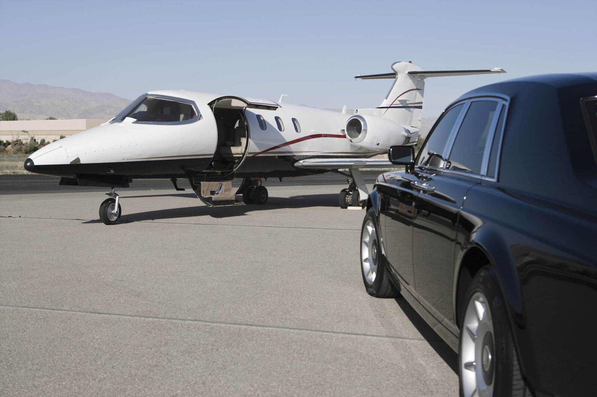 A private jet is parked next to a black car