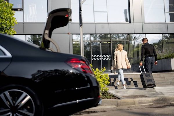 Chauffeur assisting passenger with luggage at SAN