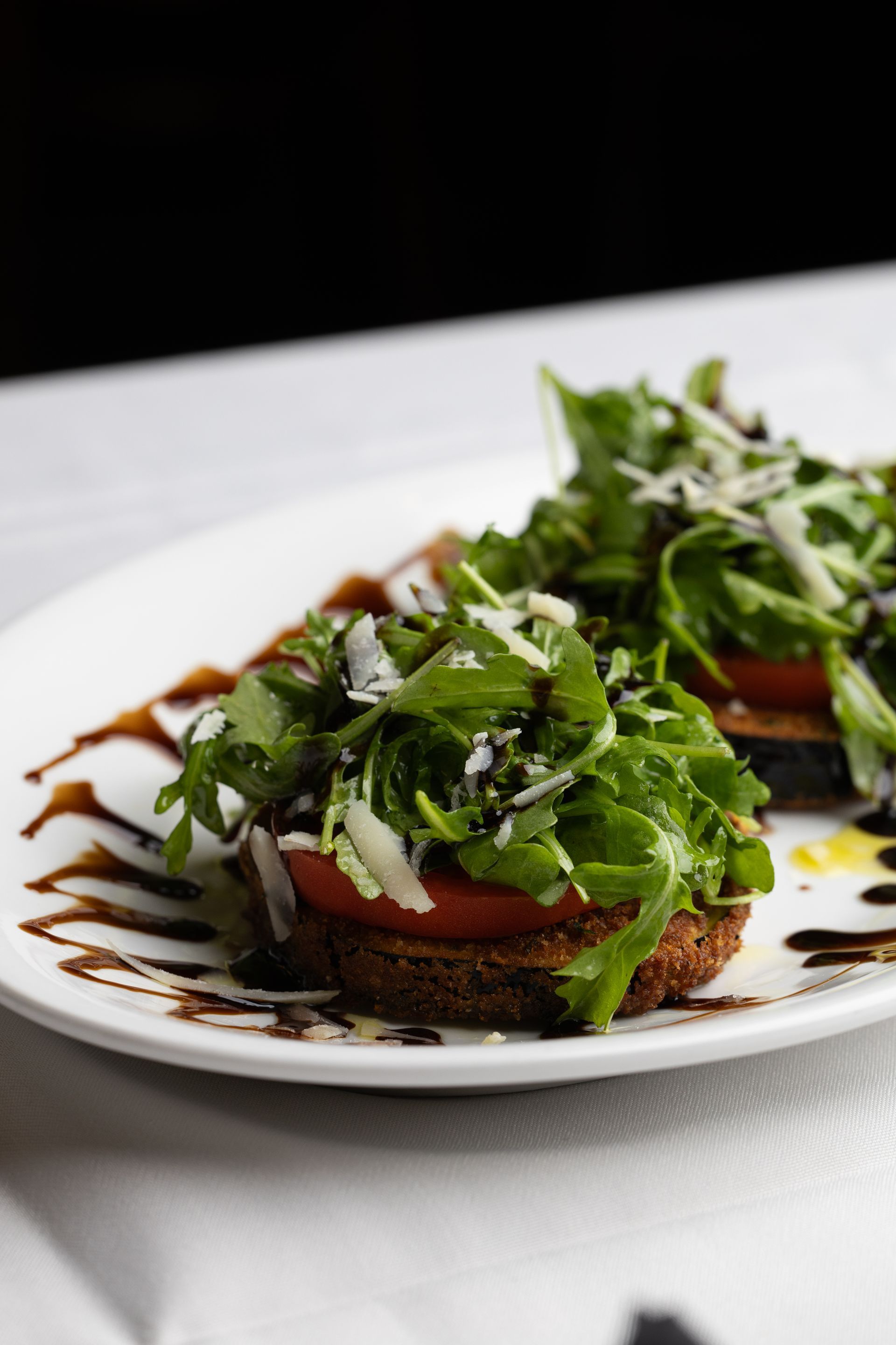 A white plate topped with a salad and tomatoes on a table.