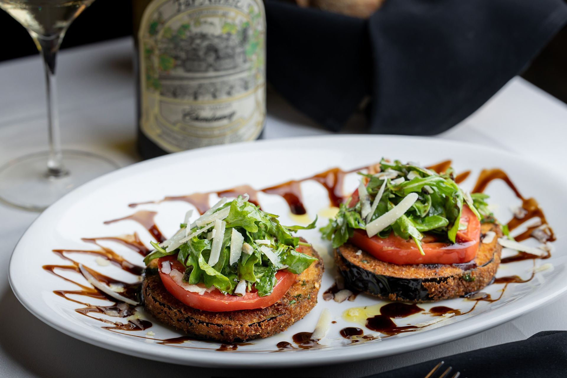 A plate of food with a bottle of wine in the background