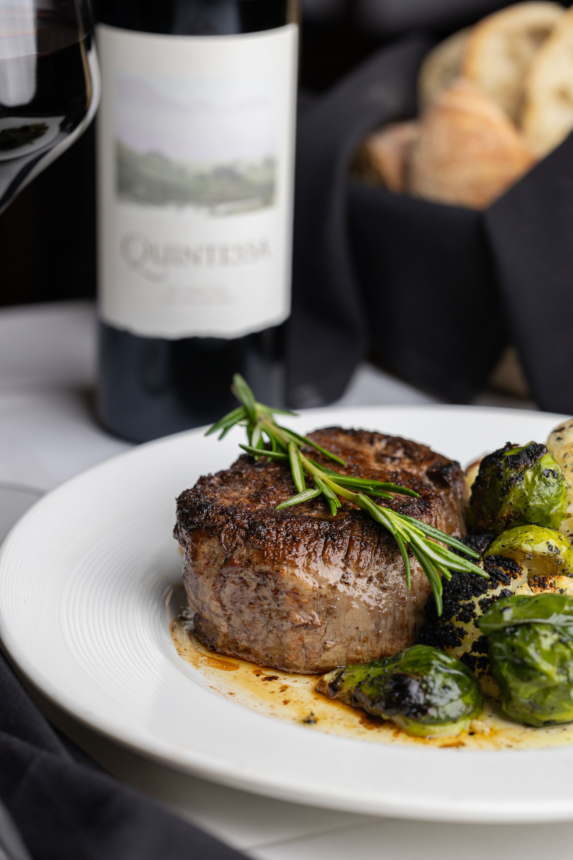 A plate of food with a bottle of wine in the background.