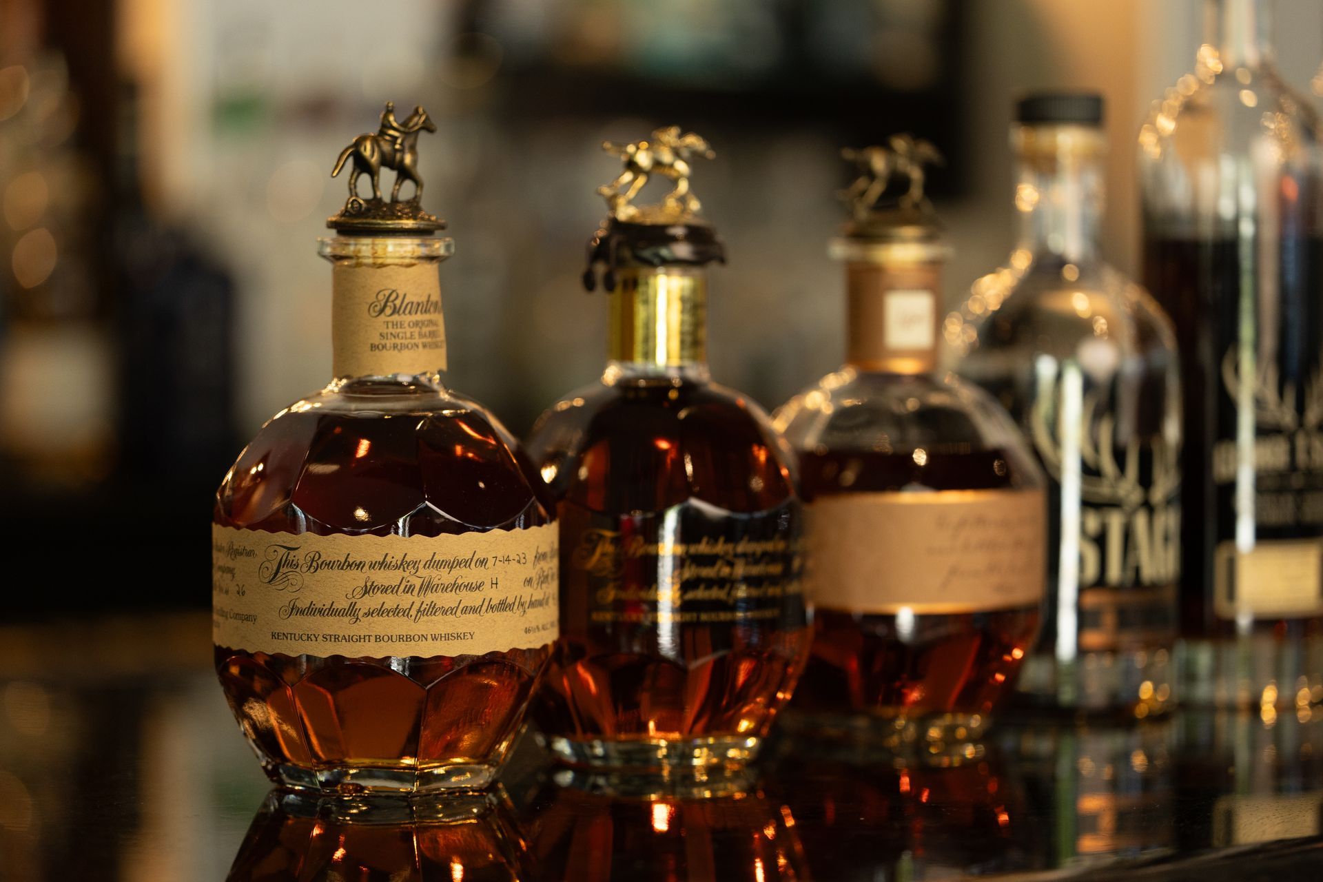 Four bottles of whiskey are sitting on a bar.