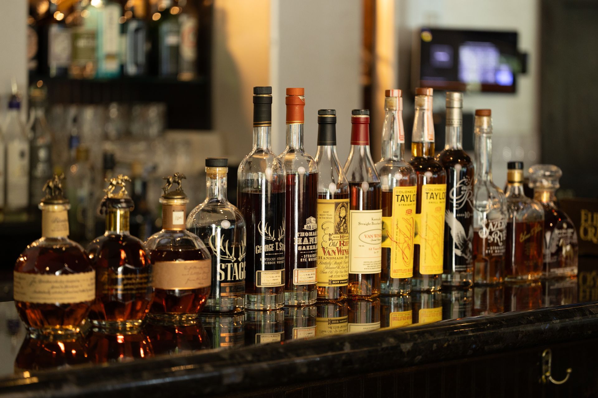 Many bottles of liquor are lined up on a bar