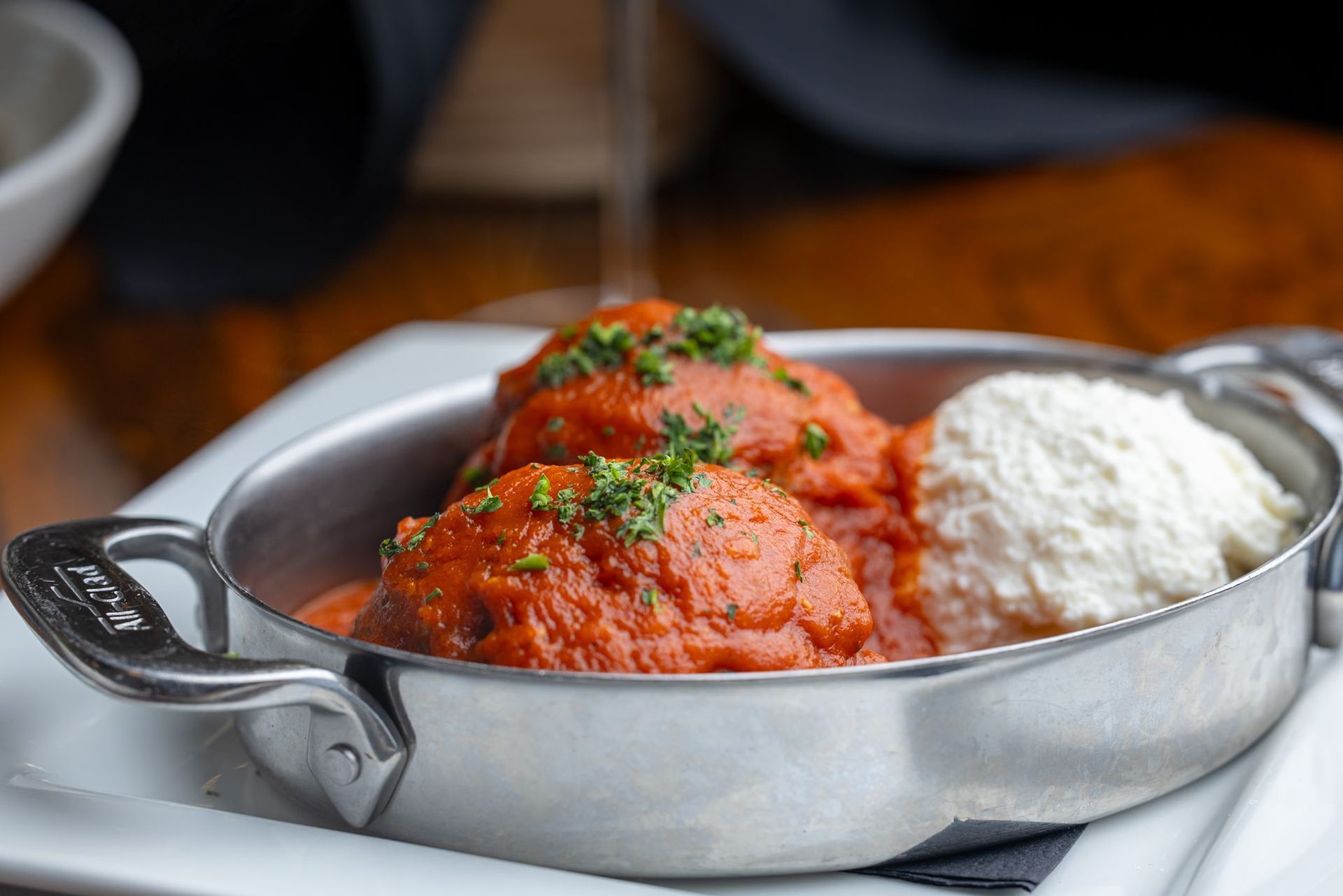 A pan filled with meatballs and sauce on a white plate.
