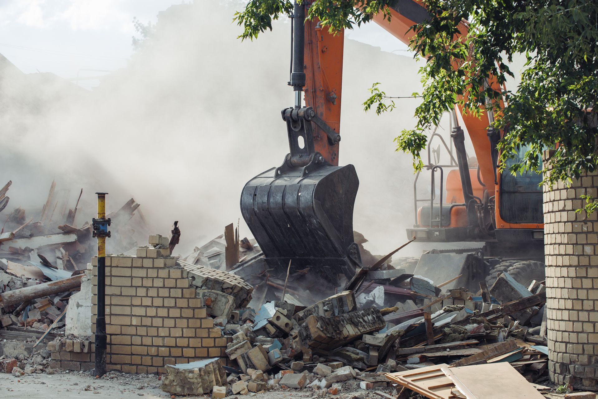 A large excavator is demolishing a brick building.