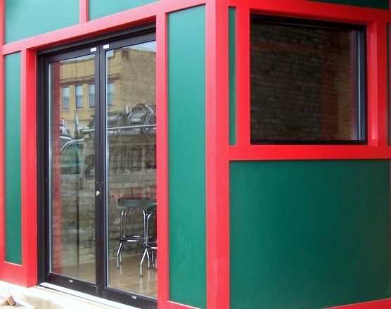 A green and red building with a sliding glass door