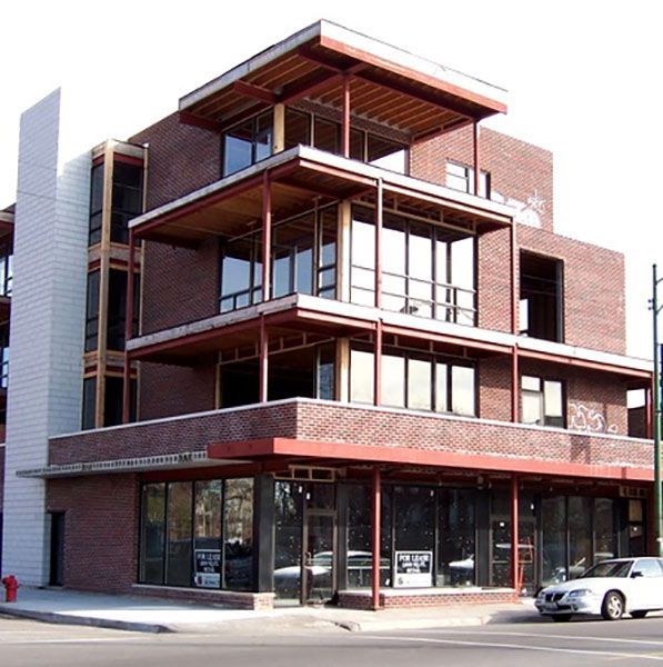 A white car is parked in front of a large brick building