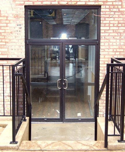 A brick building with a glass door and stairs